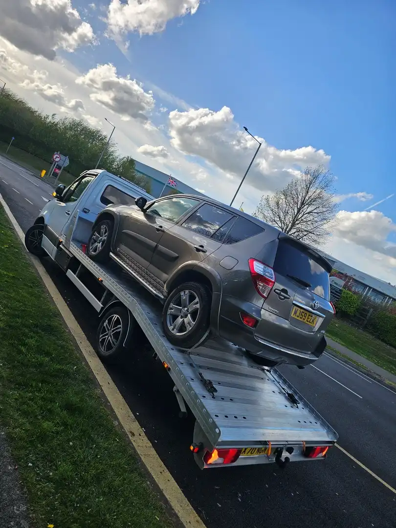 Breakdown recovery service flatbed truck loading a broken down car onto the bed with winch and straps