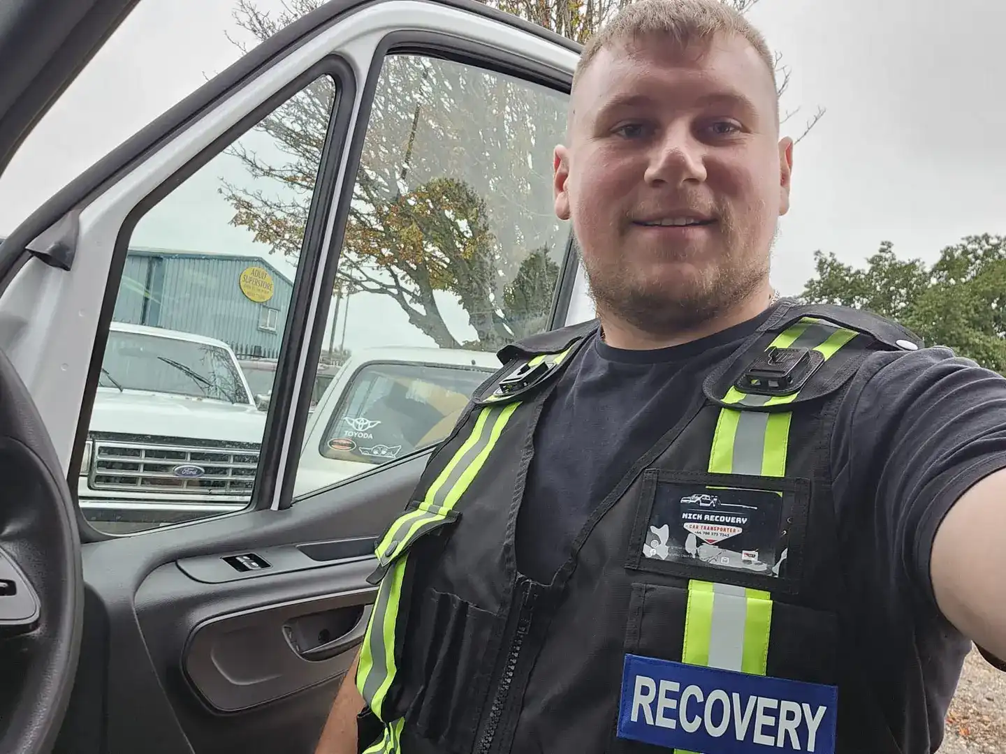 Nick from Nick Recovery standing next to his flatbed recovery truck at the Corby depot on A43 with company logo visible